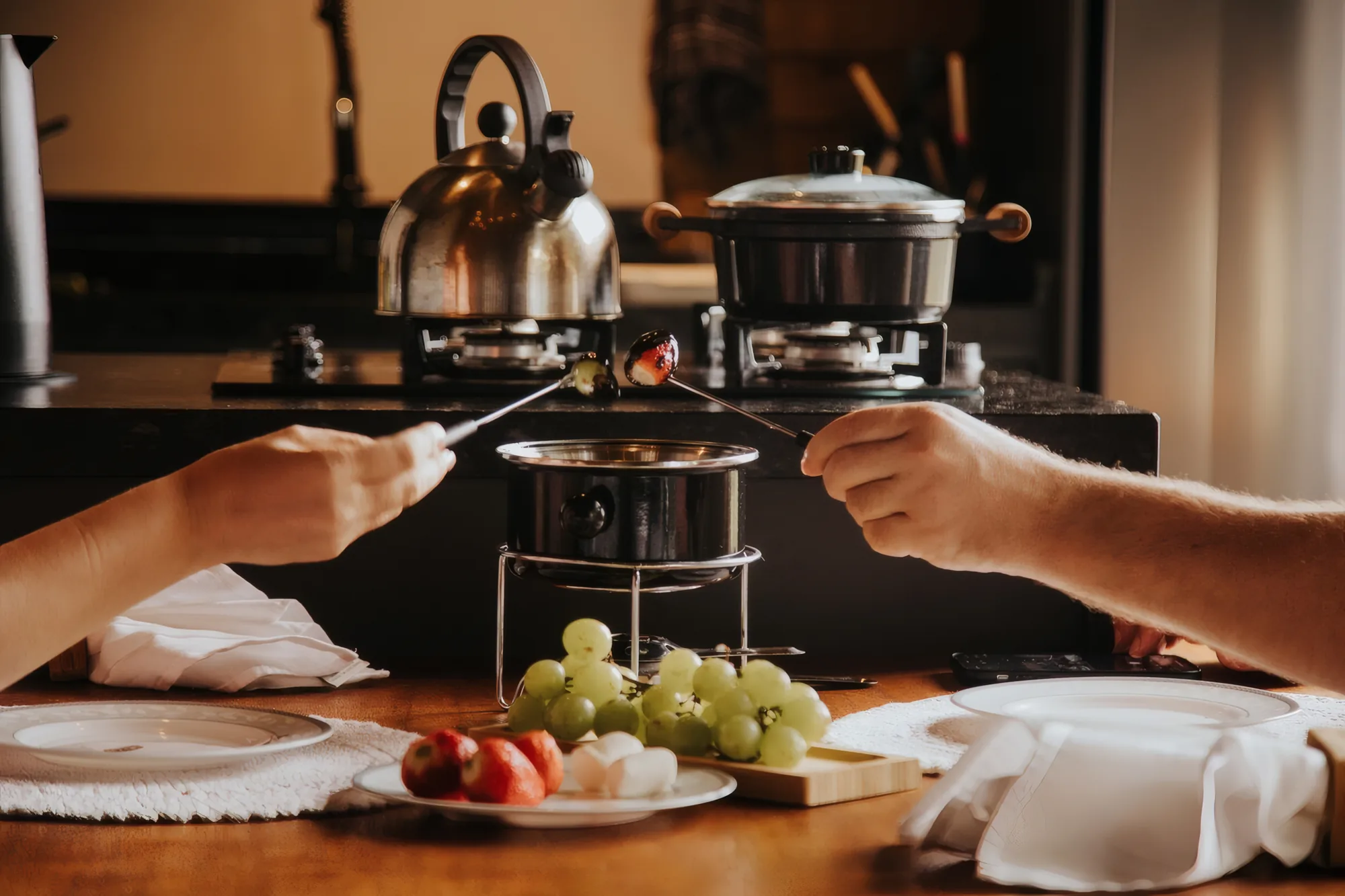 Fondue servido na mesa da cabana, com uvas e frutas