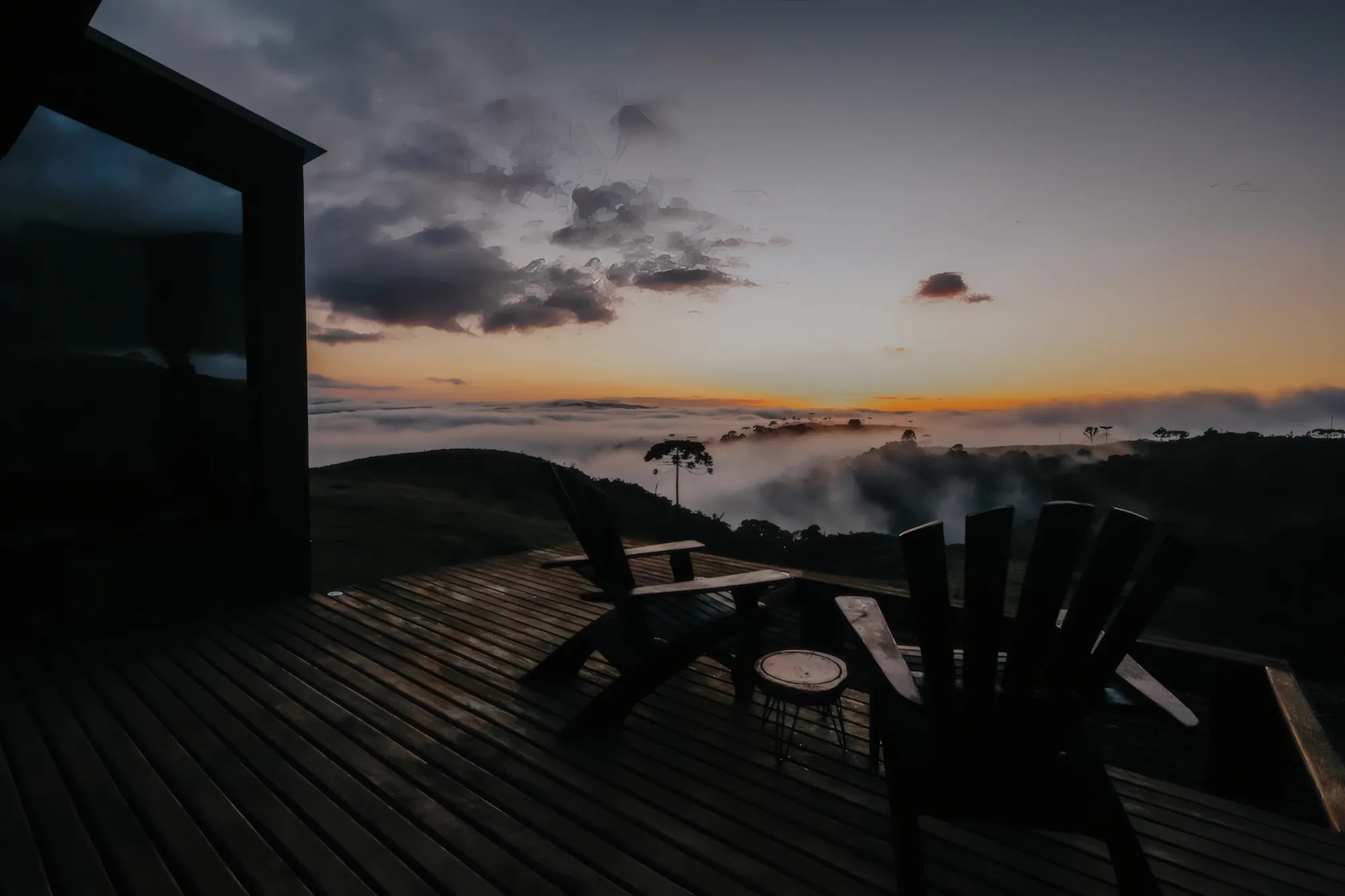 Deck com cadeiras ao entardecer, mar de nuvens no vale
