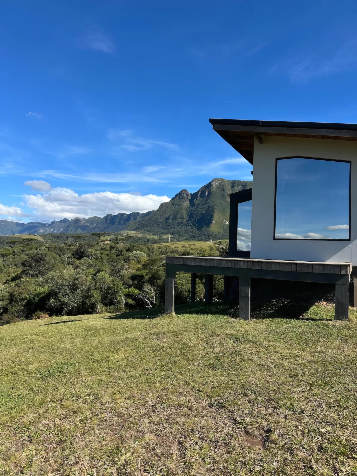 Fachada da Sunrise Home com janela panorâmica e montanhas ao fundo
