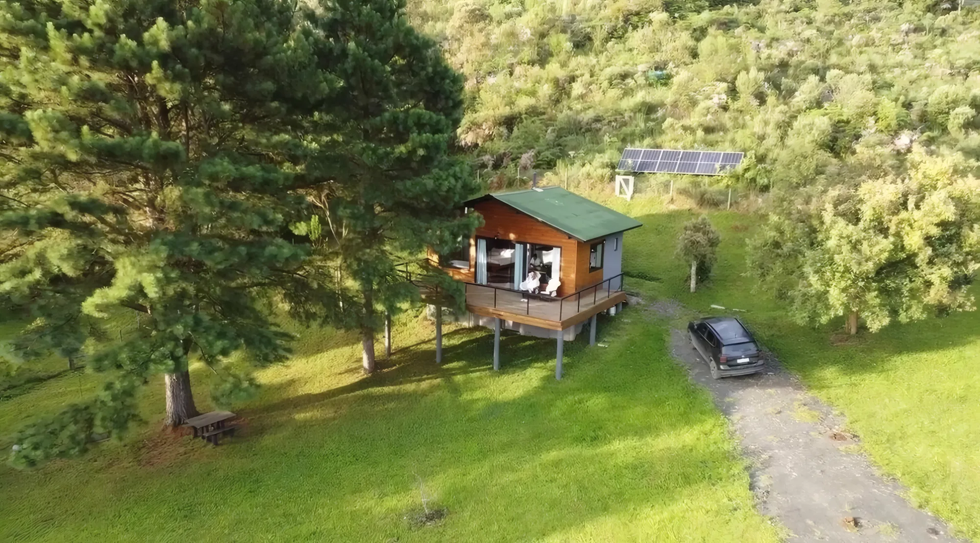 Vista aérea da Storm Ecohouse no meio da mata, com a estrada de acesso